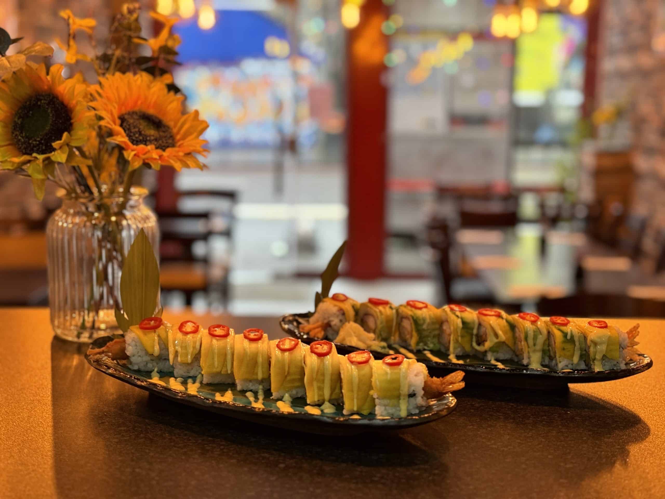 A table with two plates of sushi and flowers, creating a delightful and appetizing arrangement.